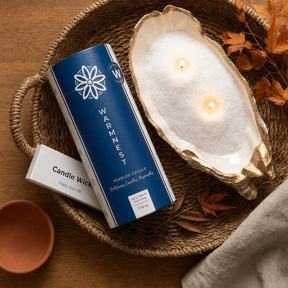 Flat lay of the Warmnest Pearled Candle tube and an oyster shell candle on a rattan tray with autumn maple leaves